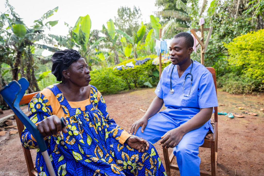 A young African doctor pay a visit to an old ill woman. Home visit to a sick elder.