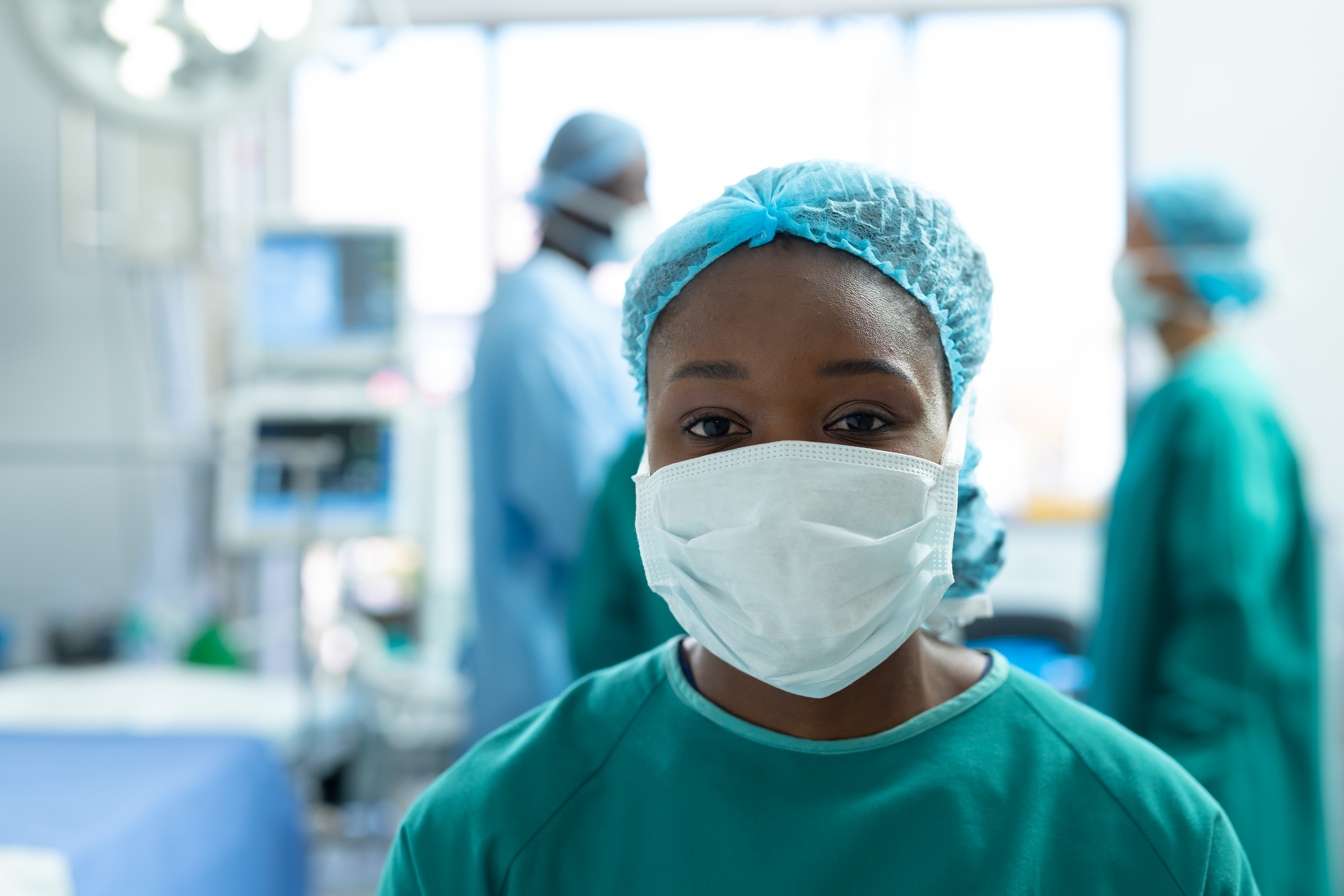 Portrait of african american female surgeon in face mask in operating theatre, with copy space. Hospital, medical and healthcare services.